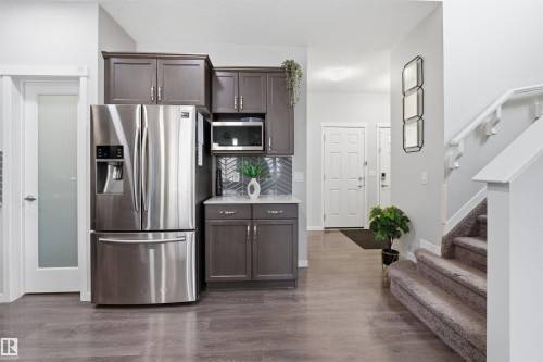 Kitchen featuring dark wood finish cabinets, stainless steel appliances, dark wood-type flooring, and backsplash - 5112 Andison Close, Edmonton, AB - Indoor