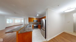 Kitchen featuring wood finish cabinets, stainless steel appliances, a peninsula, a baseboard heating unit, and light tile patterned floors - 