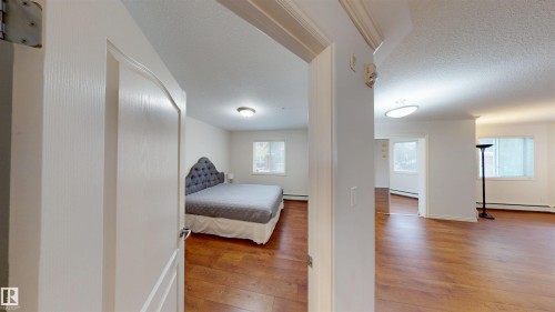 Bedroom with light wood finished floors, a textured ceiling, and a baseboard heating unit - 115 9938 104 St, Edmonton, AB - Indoor Photo Showing Other Room