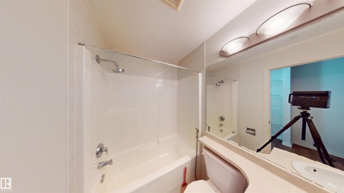 Full bath featuring a textured ceiling, vanity, and shower / bath combination - 115 9938 104 St, Edmonton, AB - Indoor Photo Showing Bathroom