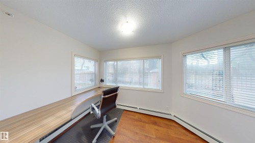 Unfurnished office featuring light wood-style flooring, a textured ceiling, and a baseboard heating unit - 115 9938 104 St, Edmonton, AB - Indoor Photo Showing Other Room