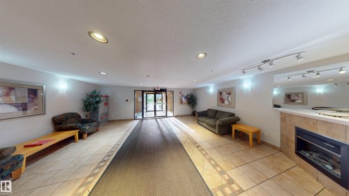 Building lobby with recessed lighting and a textured ceiling - 115 9938 104 St, Edmonton, AB - Indoor Photo Showing Other Room With Fireplace