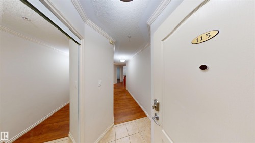 Corridor with a textured ceiling, light tile patterned flooring, and crown molding - 115 9938 104 St, Edmonton, AB - Indoor Photo Showing Other Room