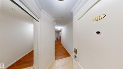 Corridor with a textured ceiling, light tile patterned flooring, and crown molding - 