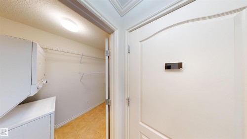 Laundry area featuring stacked washer / drying machine, a textured ceiling, and light tile patterned floors - 115 9938 104 St, Edmonton, AB - Indoor Photo Showing Other Room