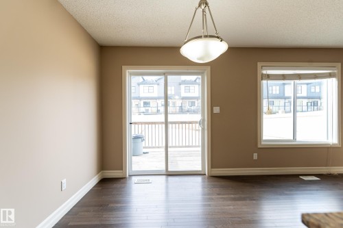 Unfurnished dining area with a textured ceiling and dark wood-style floors - 1118 162 Street, Edmonton, AB - Indoor Photo Showing Other Room