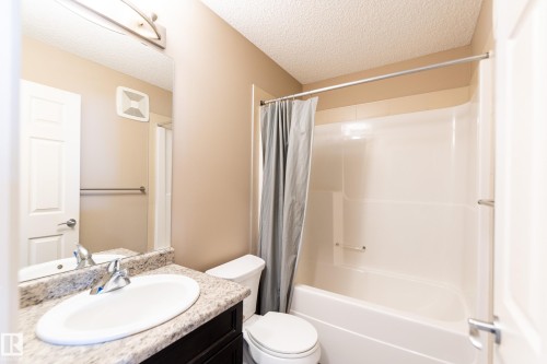 Bathroom with a textured ceiling, vanity, and shower / bath combination with curtain - 1118 162 Street, Edmonton, AB - Indoor Photo Showing Bathroom