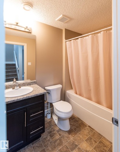 Full bath featuring vanity, shower / bath combo, and a textured ceiling - 1118 162 Street, Edmonton, AB - Indoor Photo Showing Bathroom