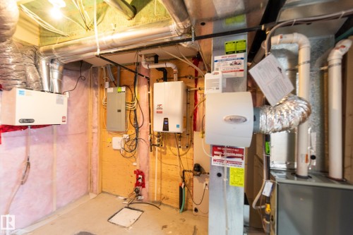 Utility room featuring electric panel, tankless water heater, and heating unit - 1118 162 Street, Edmonton, AB - Indoor Photo Showing Basement