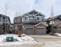 View of front of property with driveway, an attached garage, stone siding, and a residential view - 1118 162 Street, Edmonton, AB  - Outdoor With Facade 