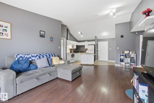 Living area featuring vaulted ceiling, dark wood-type flooring, and rail lighting - 421 155 Edwards Drive, Edmonton, AB - Indoor Photo Showing Living Room