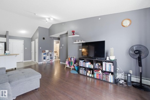 Living area with dark wood-type flooring and a baseboard heating unit - 421 155 Edwards Drive, Edmonton, AB - Indoor Photo Showing Living Room