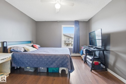 Bedroom featuring wood finished floors, ceiling fan, a baseboard heating unit, and a textured ceiling - 421 155 Edwards Drive, Edmonton, AB - Indoor Photo Showing Bedroom