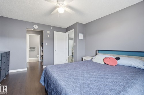 Bedroom with a textured ceiling, dark wood-type flooring, and a ceiling fan - 421 155 Edwards Drive, Edmonton, AB - Indoor Photo Showing Bedroom