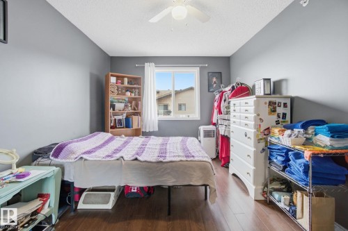 Bedroom with dark wood-style flooring, a ceiling fan, and a textured ceiling - 421 155 Edwards Drive, Edmonton, AB - Indoor Photo Showing Bedroom