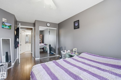 Bedroom with a closet, dark wood-type flooring, a textured ceiling, a ceiling fan, and connected bathroom - 421 155 Edwards Drive, Edmonton, AB - Indoor Photo Showing Bedroom