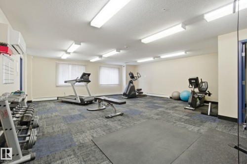 Workout room featuring a textured ceiling and a baseboard radiator - 421 155 Edwards Drive, Edmonton, AB - Indoor Photo Showing Gym Room