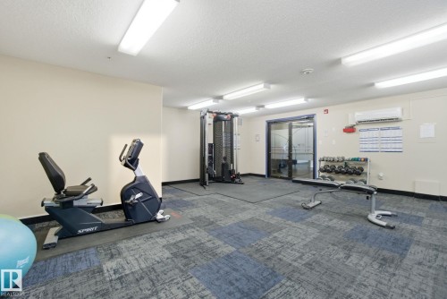 Gym with a textured ceiling and a mini split for heating / cooling - 421 155 Edwards Drive, Edmonton, AB - Indoor Photo Showing Gym Room