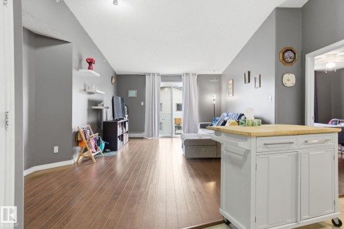 Kitchen with open floor plan, a center island, white cabinets, light wood-style flooring, and wooden counters - 421 155 Edwards Drive, Edmonton, AB - Indoor
