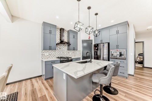 Kitchen featuring gray cabinetry, stainless steel appliances, light wood finished floors, and a kitchen breakfast bar - 5110 23A Avenue, Edmonton, AB - Indoor Photo Showing Kitchen With Upgraded Kitchen
