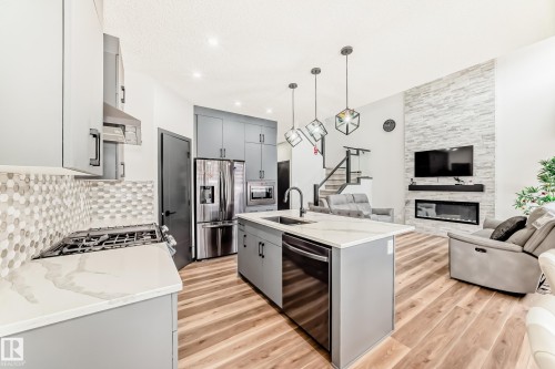 Kitchen featuring gray cabinetry, open floor plan, a center island with sink, and stainless steel appliances - 5110 23A Avenue, Edmonton, AB - Indoor Photo Showing Kitchen With Upgraded Kitchen