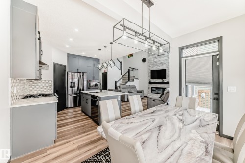 Kitchen featuring open floor plan, an island with sink, stainless steel refrigerator with ice dispenser, a kitchen breakfast bar, and light wood finished floors - 5110 23A Avenue, Edmonton, AB - Indoor
