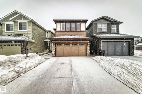 View of front of property featuring stone siding, driveway, and a garage - 5110 23A Avenue, Edmonton, AB - Outdoor With Facade