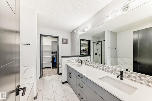 Full bathroom featuring double vanity, a bath, a stall shower, a walk in closet, and light marble finish floors - 5110 23A Avenue, Edmonton, AB - Indoor Photo Showing Bathroom