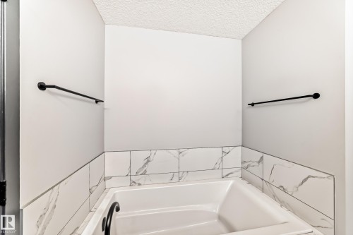 Full bath with a garden tub and a textured ceiling - 5110 23A Avenue, Edmonton, AB - Indoor Photo Showing Laundry Room