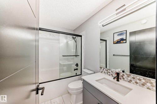 Full bath featuring vanity, combined bath / shower with glass door, and a textured ceiling - 5110 23A Avenue, Edmonton, AB - Indoor Photo Showing Bathroom