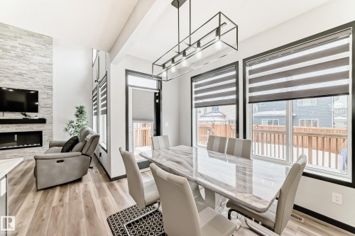 Dining room featuring light wood-style floors and a tiled fireplace - 5110 23A Avenue, Edmonton, AB - Indoor Photo Showing Dining Room