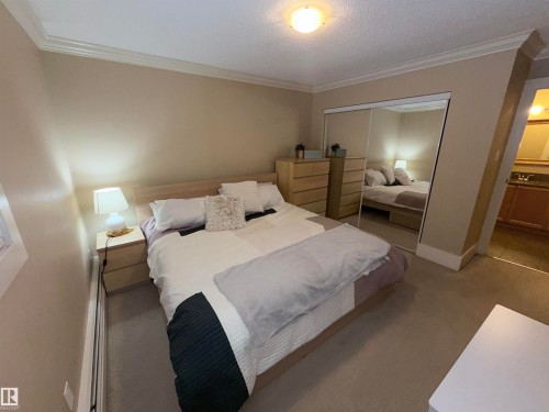 Bedroom with crown molding, a closet, carpet, baseboard heating, and a textured ceiling - 102 11303 103 Avenue, Edmonton, AB - Indoor Photo Showing Bedroom