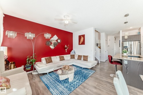 Living room with light wood finished floors, a ceiling fan, and a chandelier - 3059 Checknita Way, Edmonton, AB - Indoor
