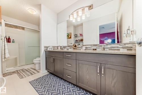 Full bathroom featuring double vanity, a shower stall, light tile patterned flooring, a textured ceiling, and backsplash - 3059 Checknita Way, Edmonton, AB - Indoor Photo Showing Bathroom