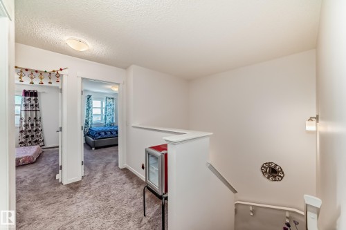 Corridor with an upstairs landing, a textured ceiling, and light carpet - 3059 Checknita Way, Edmonton, AB - Indoor Photo Showing Other Room