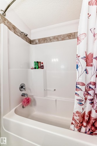 Bathroom featuring a textured ceiling and shower / bath combo with shower curtain - 3059 Checknita Way, Edmonton, AB - Indoor Photo Showing Bathroom