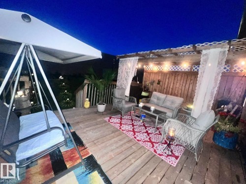 The property features a wooden deck with an overhead pergola, string lights, and a privacy fence - 3059 Checknita Way, Edmonton, AB - Outdoor With Deck Patio Veranda