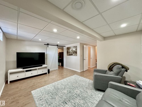Living area featuring a barn door, recessed lighting, a drop ceiling, and light wood-style floors - 4 Wolf Crescent Nw, Edmonton, AB - Indoor
