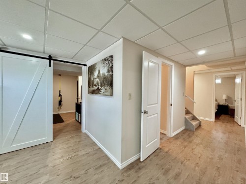 Hallway featuring light wood finished floors, a drop ceiling, a barn door, and recessed lighting - 4 Wolf Crescent Nw, Edmonton, AB - Indoor Photo Showing Other Room