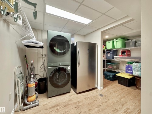 Laundry area featuring a drop ceiling, light wood finished floors, and stacked washer and clothes dryer - 4 Wolf Crescent Nw, Edmonton, AB - Indoor Photo Showing Laundry Room