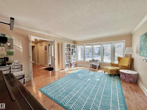 Living area featuring light wood-type flooring, a textured ceiling, and crown molding - 4 Wolf Crescent Nw, Edmonton, AB - Indoor