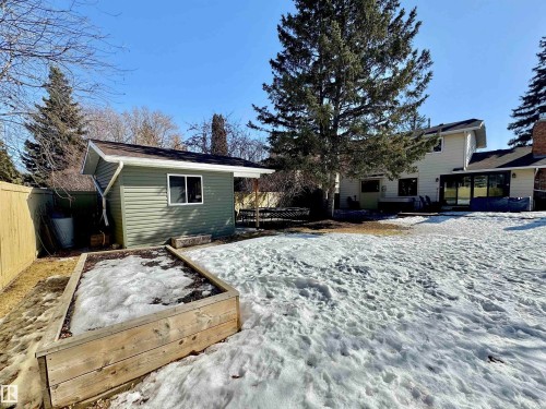 Snow covered rear of property with an outbuilding, a fenced backyard, a wooden deck, and a vegetable garden - 4 Wolf Crescent Nw, Edmonton, AB - Outdoor