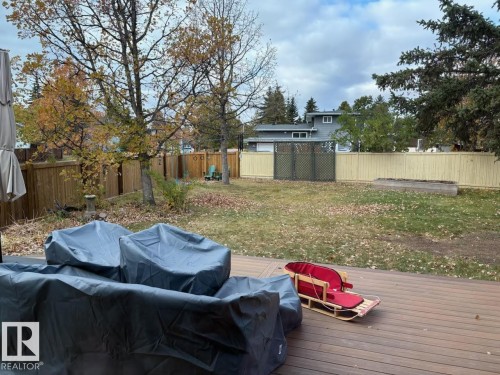 The property features an expansive backyard with a wooden fence and a raised garden bed - 4 Wolf Crescent Nw, Edmonton, AB - Outdoor With Deck Patio Veranda