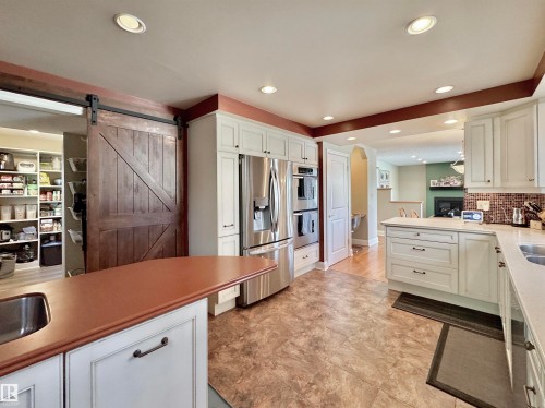 Kitchen featuring stainless steel appliances, white cabinetry, a peninsula, a barn door, and recessed lighting - 4 Wolf Crescent Nw, Edmonton, AB - Indoor Photo Showing Kitchen With Double Sink