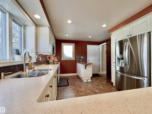Kitchen with stainless steel refrigerator with ice dispenser, white cabinetry, recessed lighting, tasteful backsplash, and dark stone counters - 4 Wolf Crescent Nw, Edmonton, AB - Indoor Photo Showing Kitchen With Double Sink
