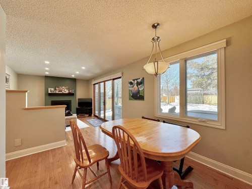 Dining space with light wood-type flooring, a textured ceiling, a fireplace, and recessed lighting - 4 Wolf Crescent Nw, Edmonton, AB - Indoor Photo Showing Dining Room
