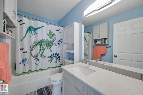 Bathroom with a textured ceiling, vanity, and shower / bathtub combination with curtain - 59 14803 Miller Boulevard, Edmonton, AB - Indoor Photo Showing Bathroom
