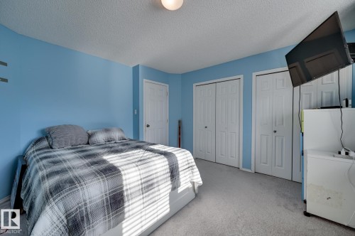Bedroom featuring carpet, two closets, and a textured ceiling - 59 14803 Miller Boulevard, Edmonton, AB - Indoor Photo Showing Bedroom