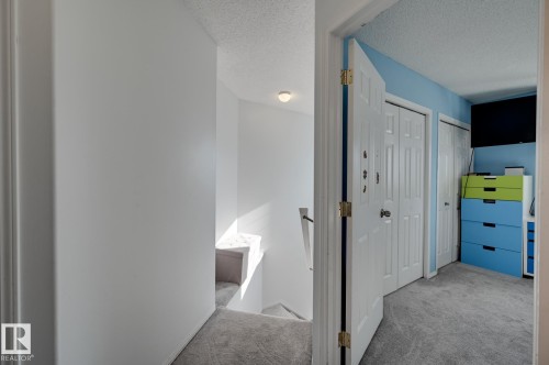 Corridor with an upstairs landing, light colored carpet, and a textured ceiling - 59 14803 Miller Boulevard, Edmonton, AB - Indoor Photo Showing Other Room