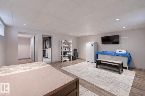 Bedroom featuring light wood-style flooring, a walk in closet, a paneled ceiling, white refrigerator, and recessed lighting - 59 14803 Miller Boulevard, Edmonton, AB - Indoor